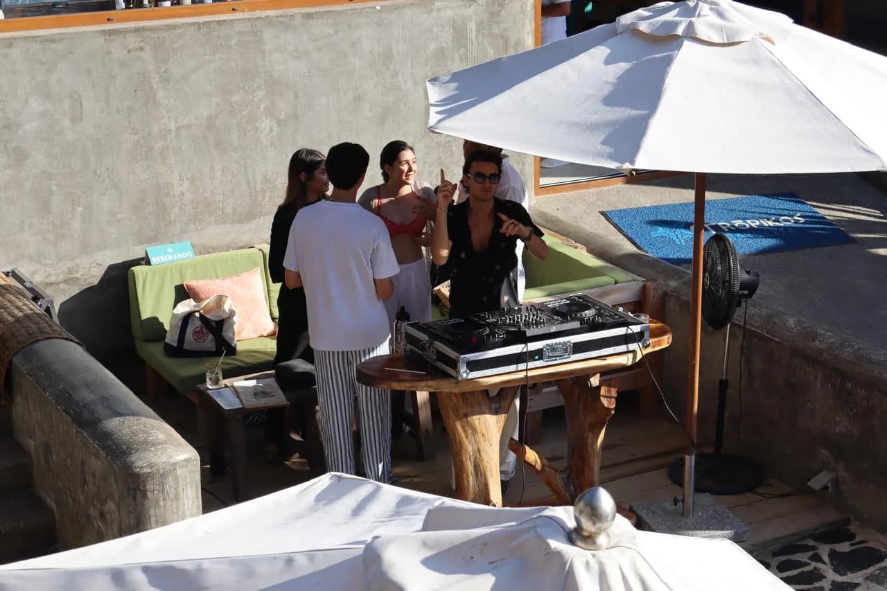 Guests gathered at the DJ booth under an umbrella at a beach club